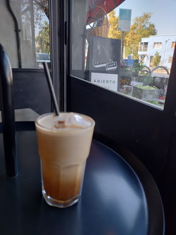 Café helado con leche en vaso de vidrio junto a la ventana del local